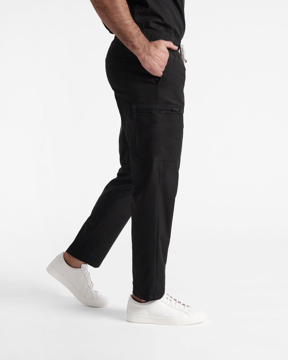 Side view of man wearing black straight leg cargo scrub pants.