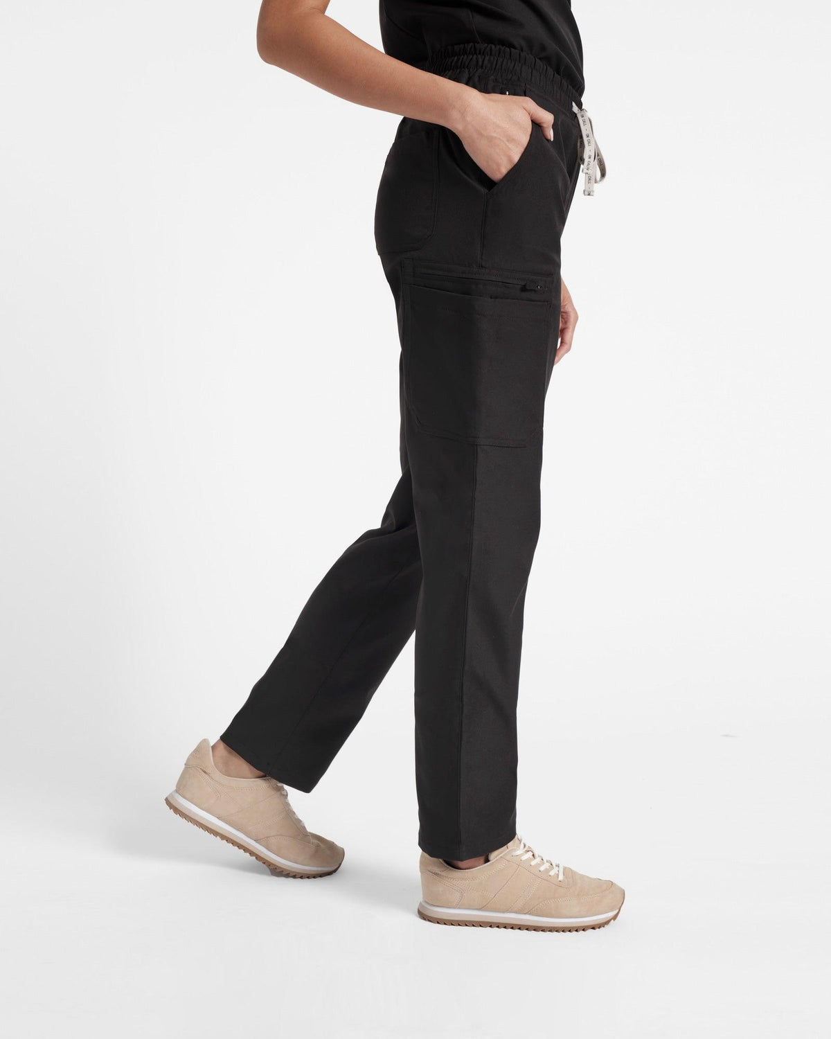 Side view of woman wearing straight leg cargo scrub pants in black.