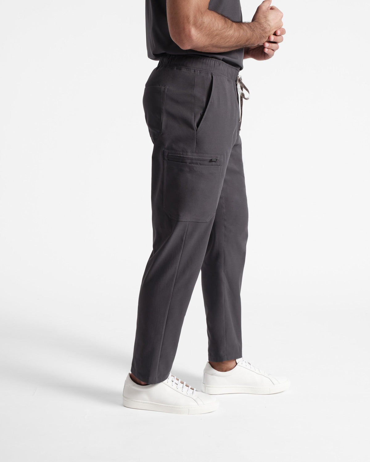 Side view of man in dark grey cargo scrub pants with a patch pocket on the leg.
