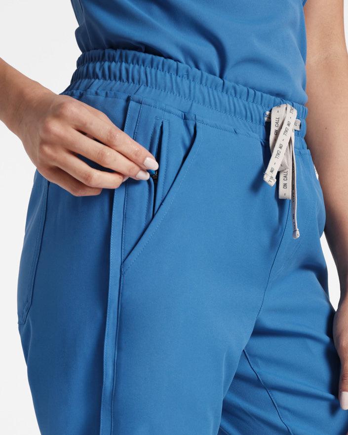 Close up of woman pulling the side zipper on her bright blue scrub pants pocket.