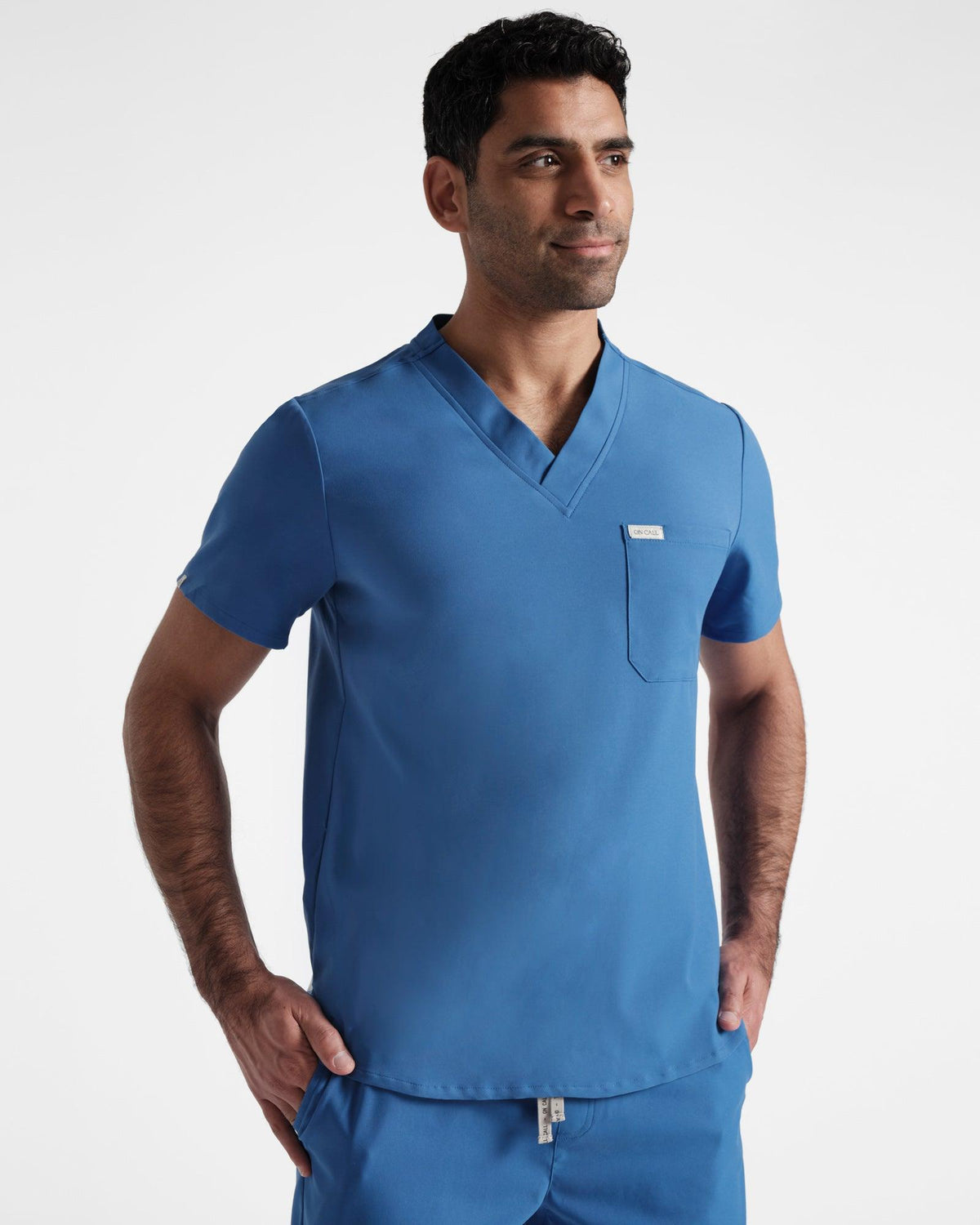 Man wearing a bright blue v-neck scrub shirt with matching scrub pants.