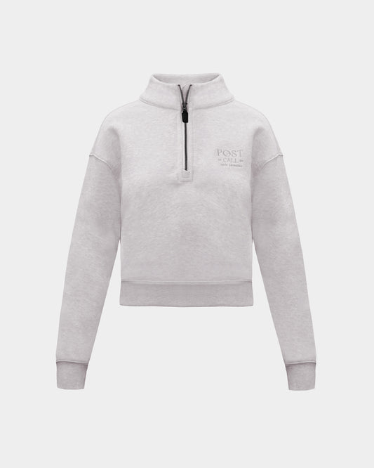 A heather grey long-sleeve quarter-zip pullover sweatshirt with a small tonal 'POST CALL' logo on the left chest, displayed on a clean light gray background.