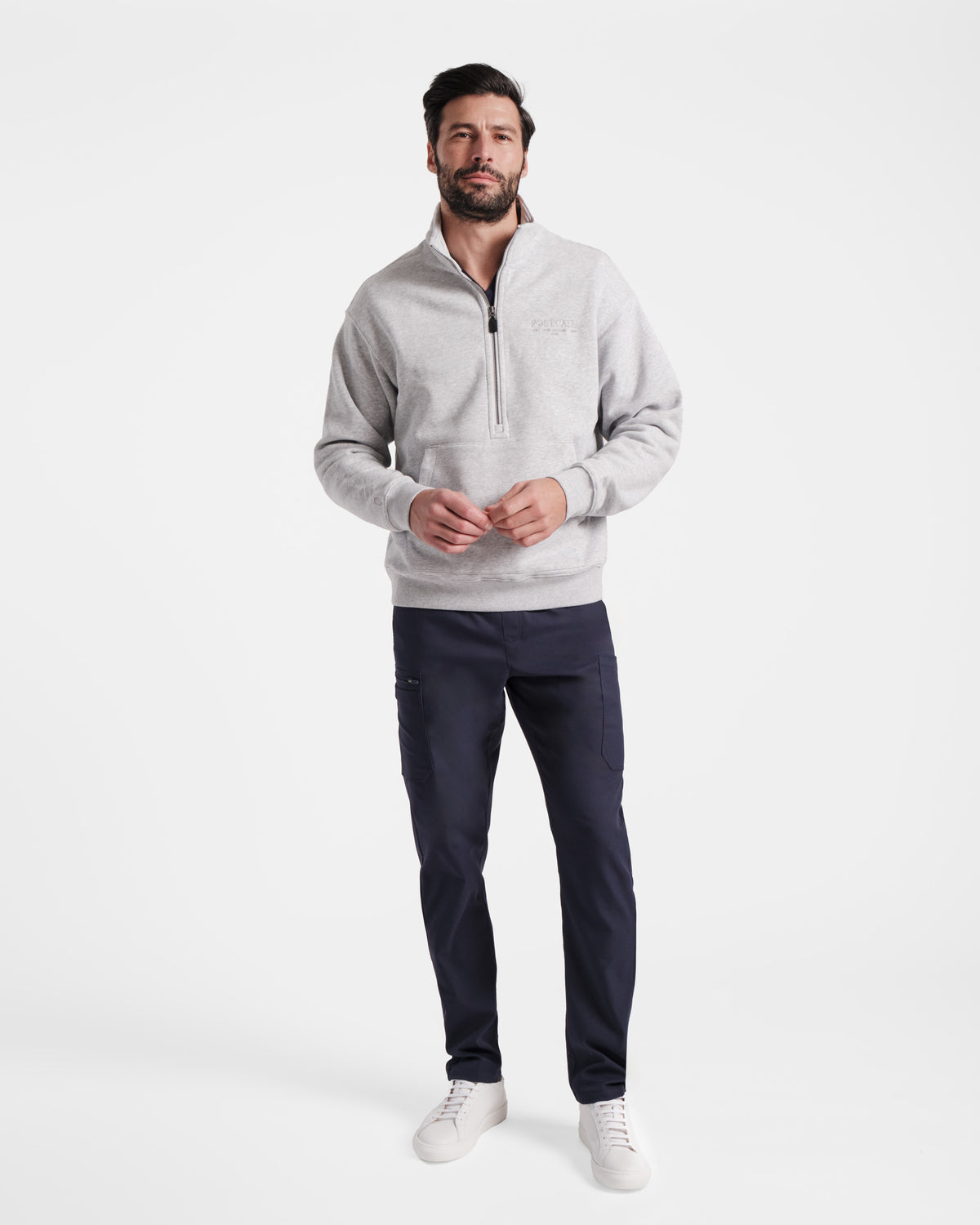 Man wearing heather grey half zip sweatshirt with a kangaroo pocket and tonal Post Call logo embroidered on the left chest.