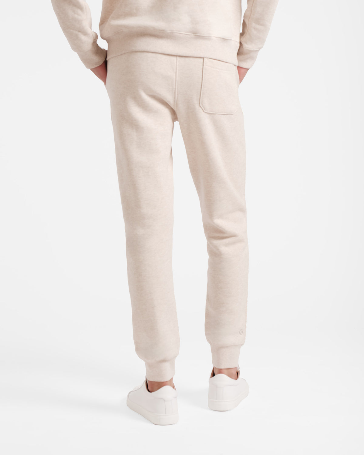 Back side view of man wearing heather beige jogger sweatpants with stretch ankle cuffs and back pocket.