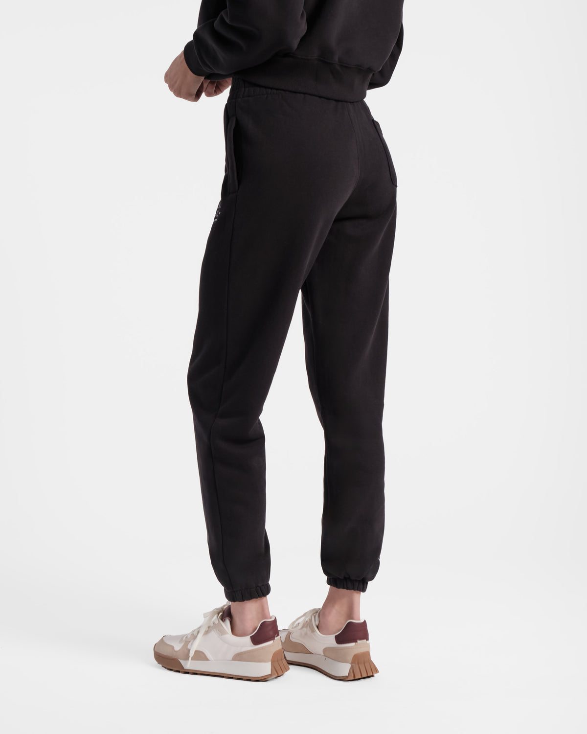 Angled back side view of woman wearing black jogger sweatpants with one back pocket on the right side.