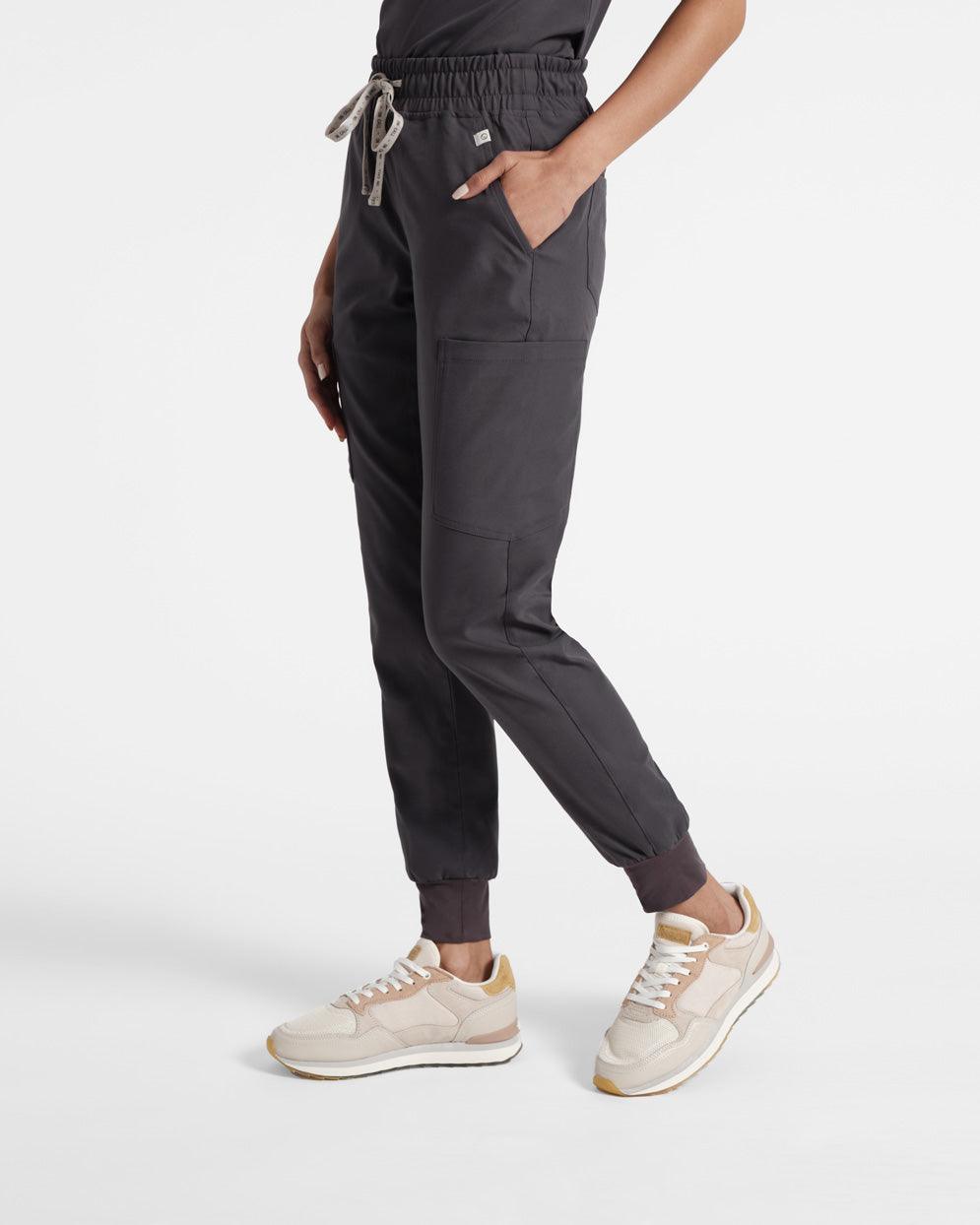 Side view of woman in dark grey cargo jogger scrub pants with a large pocket on the side of the leg.
