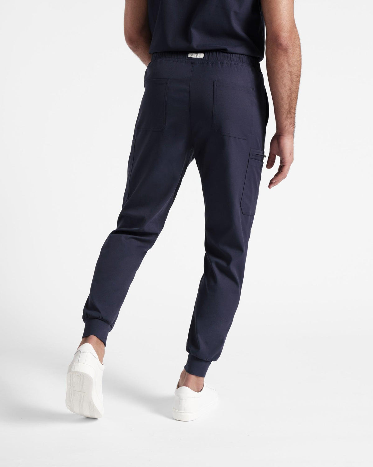 Back side view of man wearing navy cargo jogger scrub pants with two back pockets.