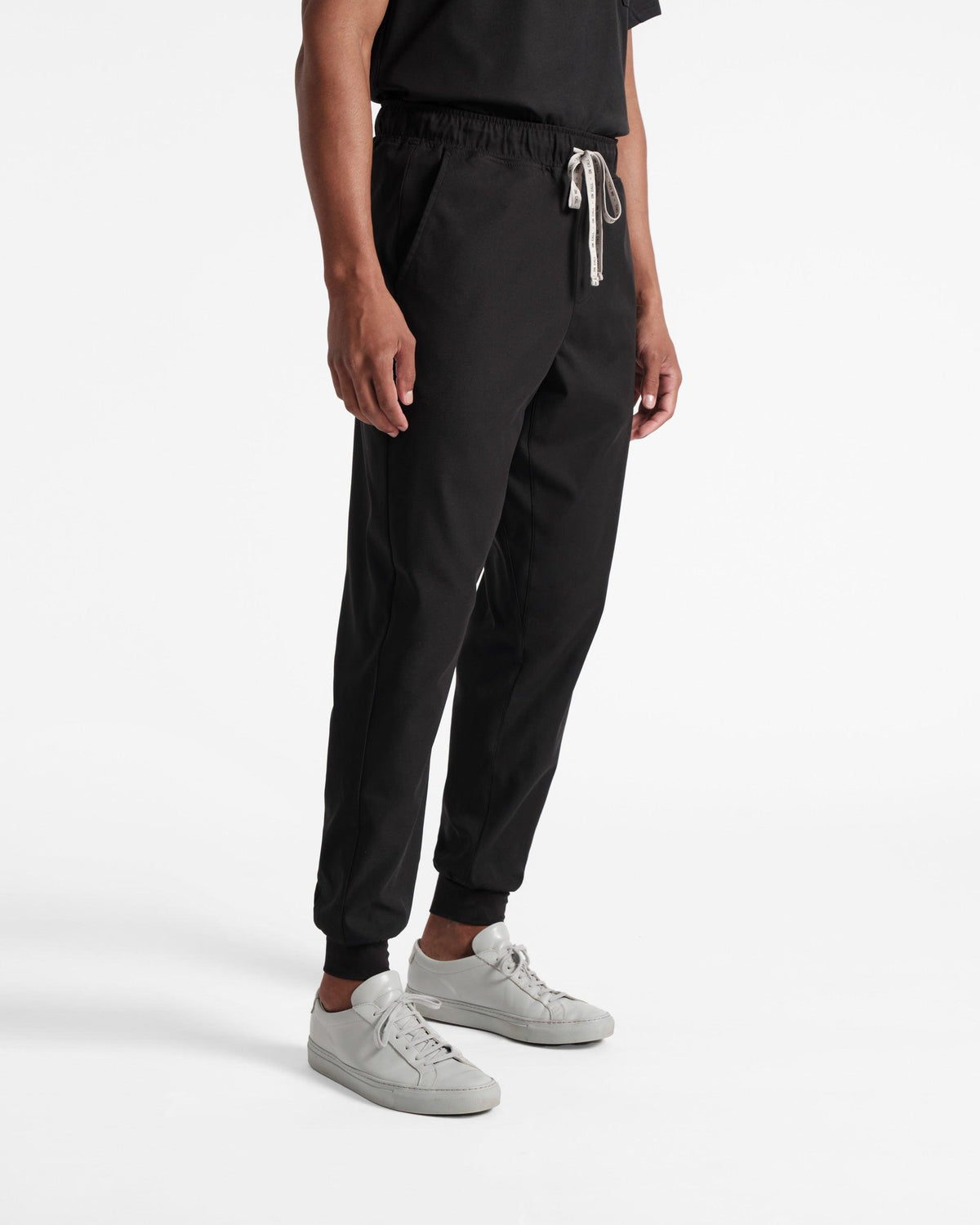 Angled side view of man wearing black jogger scrub pants with On Call branded waistband tie.