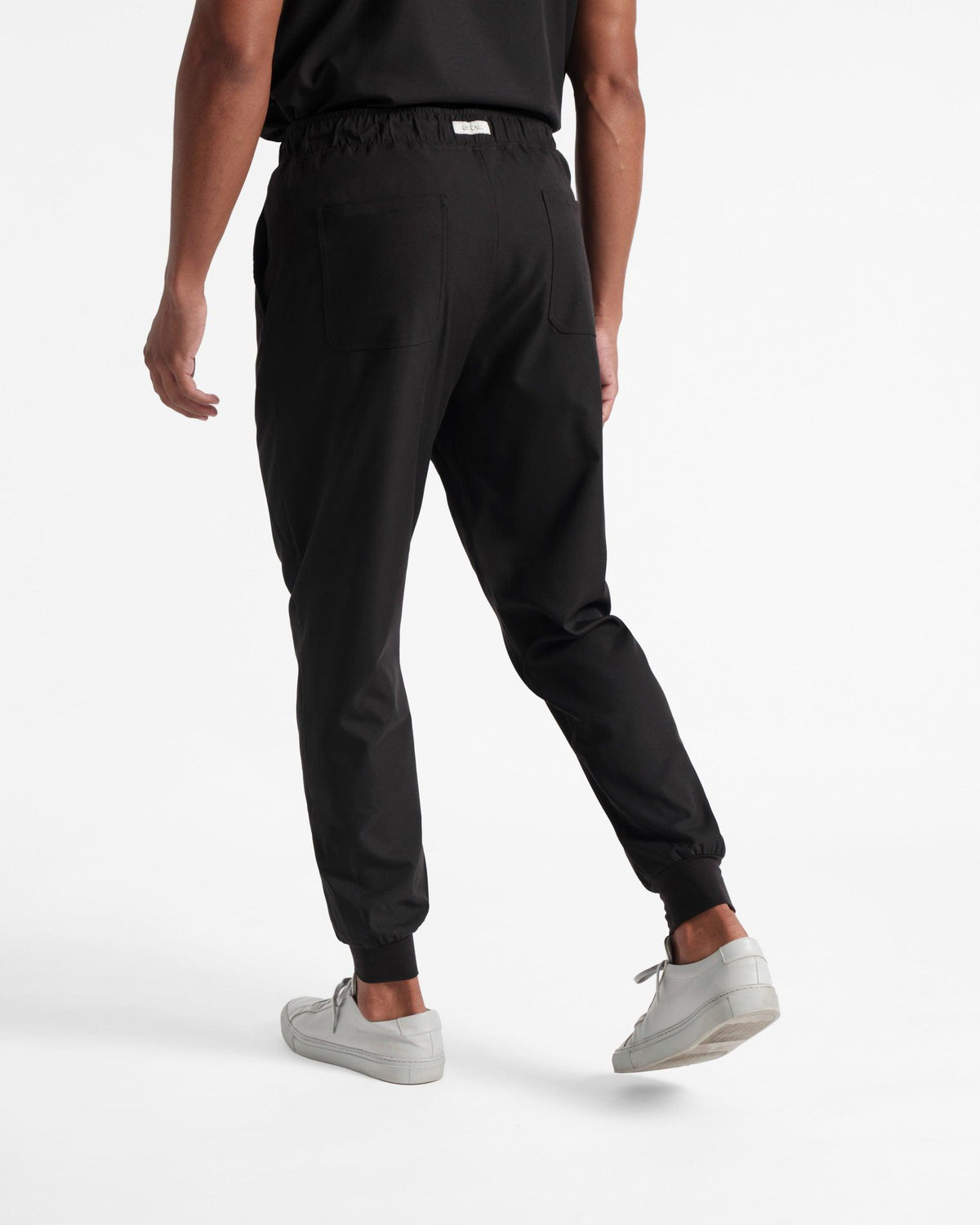 Back side view of men's jogger scrub pants in black with elasticated cuffs.