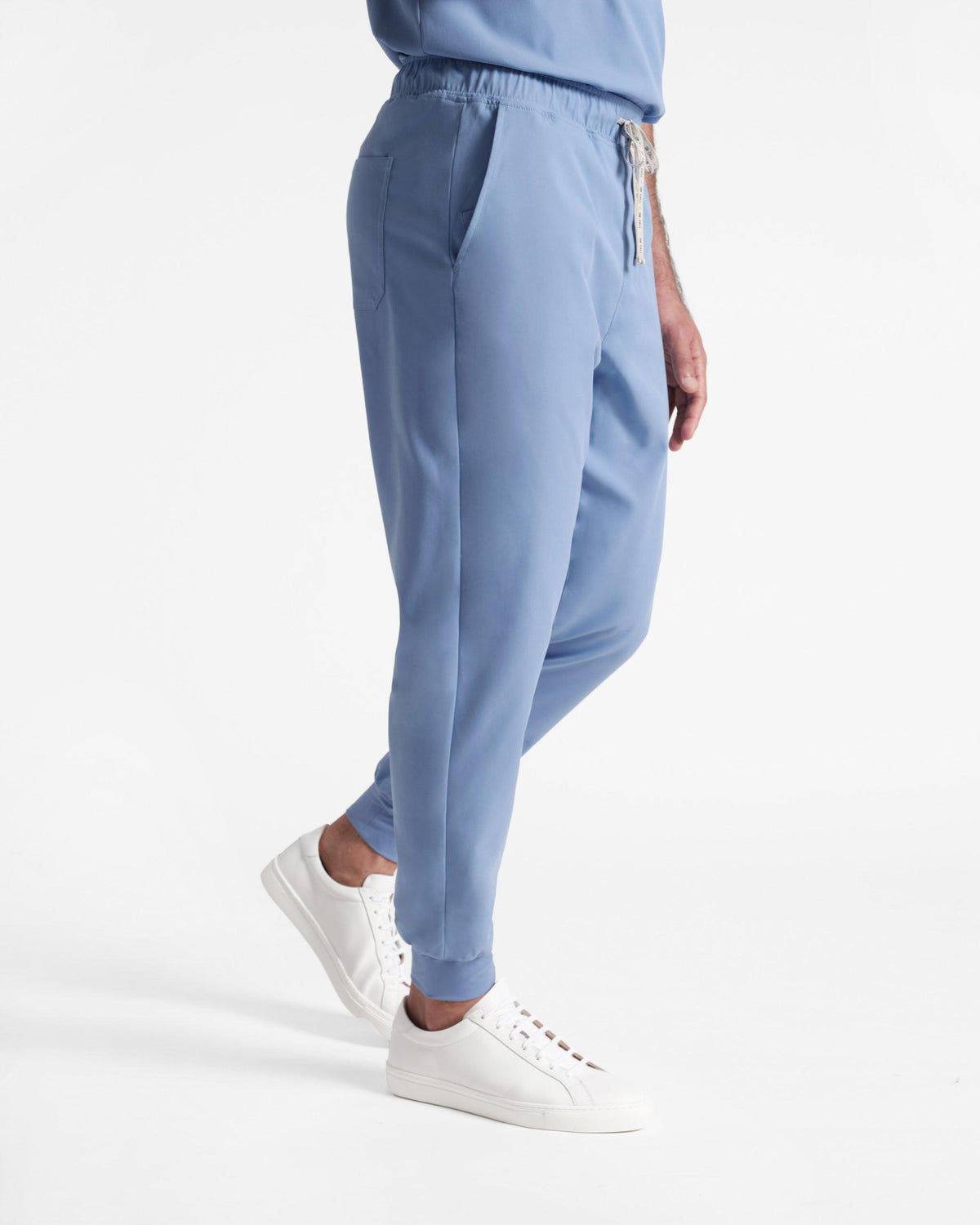 Side view of man wearing light blue jogger scrub pants with soft ribbed ankle cuffs.