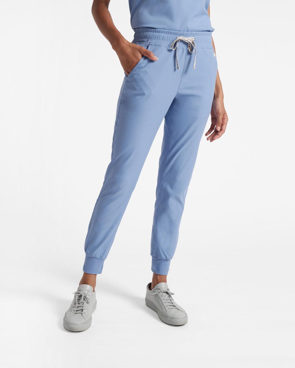 A model wearing a pair of light blue women's jogger scrub pants with elastic ankle cuffs and front pockets.