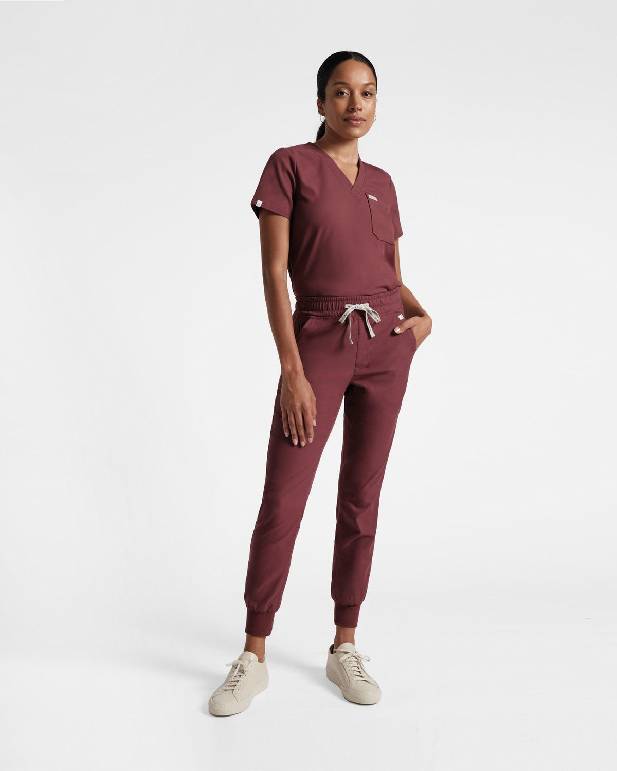 Woman in deep red jogger cargo pants and a matching v-neck top tucked in.