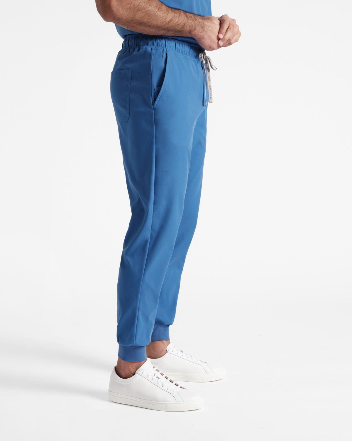 Side view of man in bright blue jogger scrub pants with soft ribbed ankle cuffs.