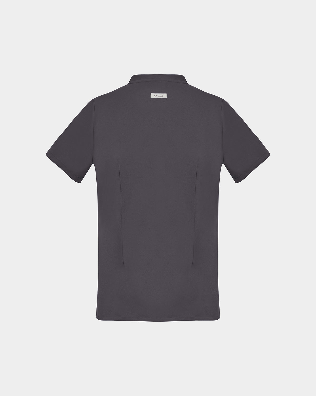 A dark gray short-sleeve scrub shirt shown from the back, featuring two subtle darts and a small rectangular brand label at the collar, set against a solid light gray background.