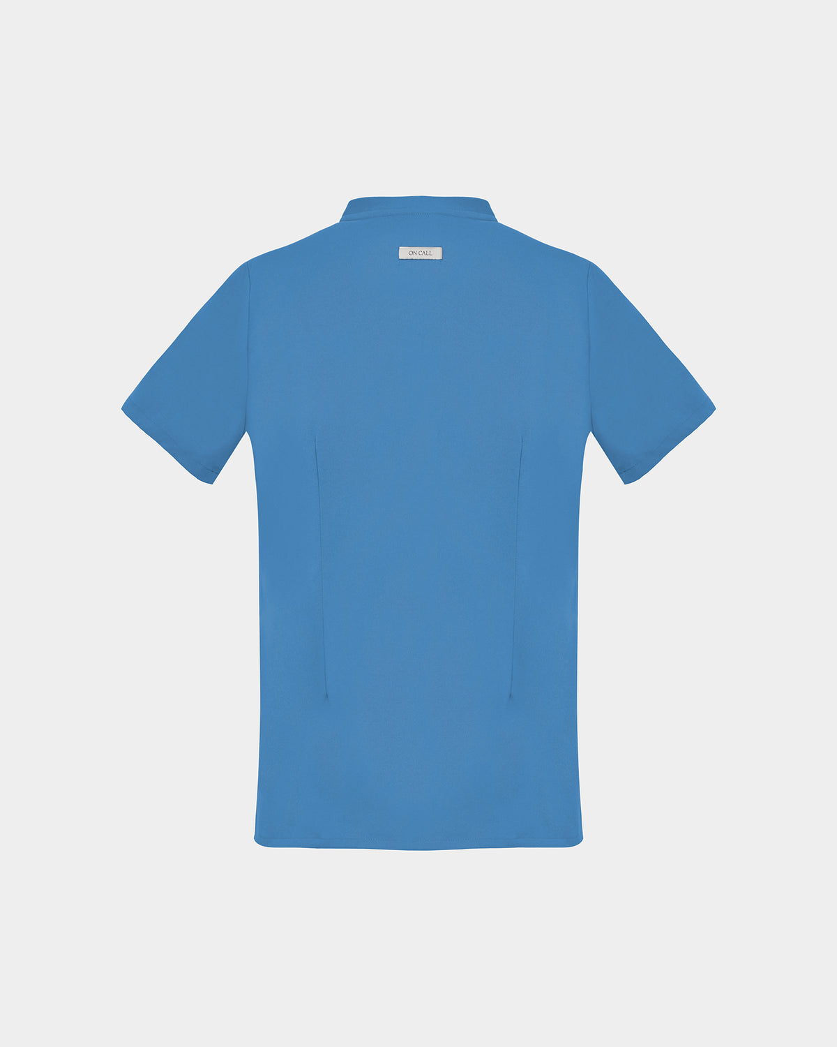 A short-sleeve scrub shirt in a solid bright blue color, featuring two subtle darts, shown from the back against a light gray background.
