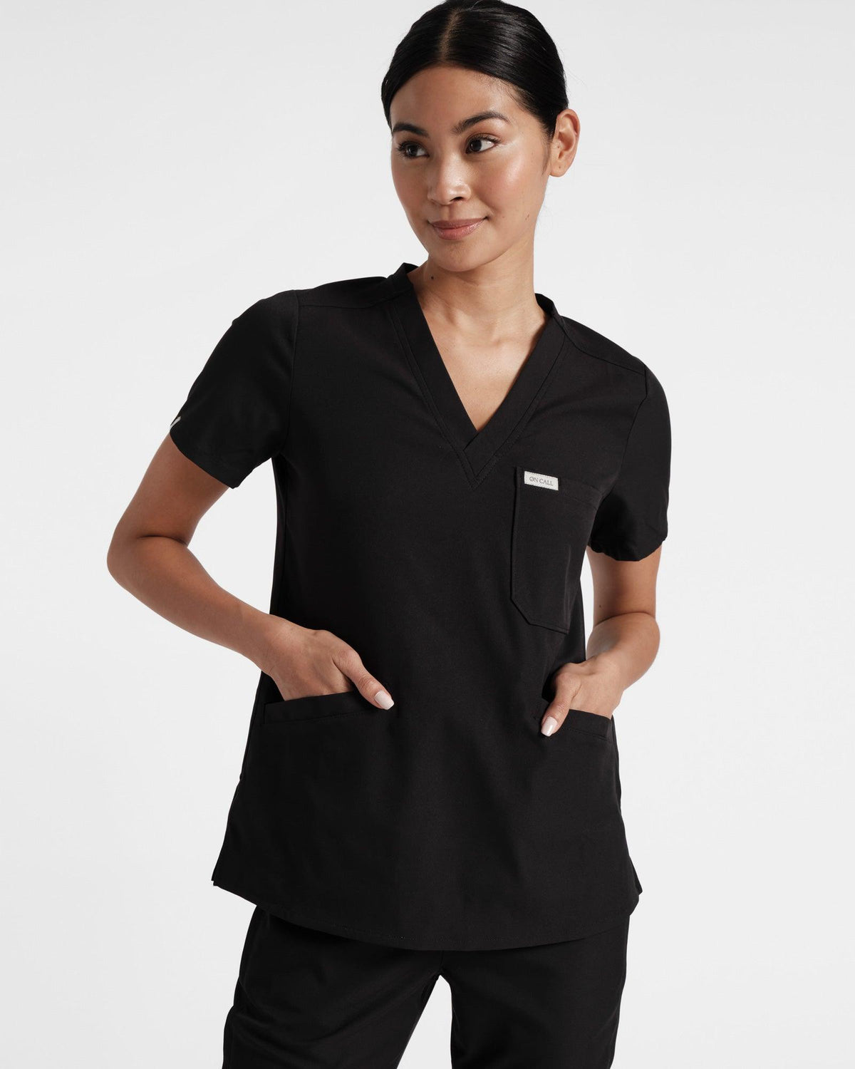 Black scrub top with three pockets on model.
