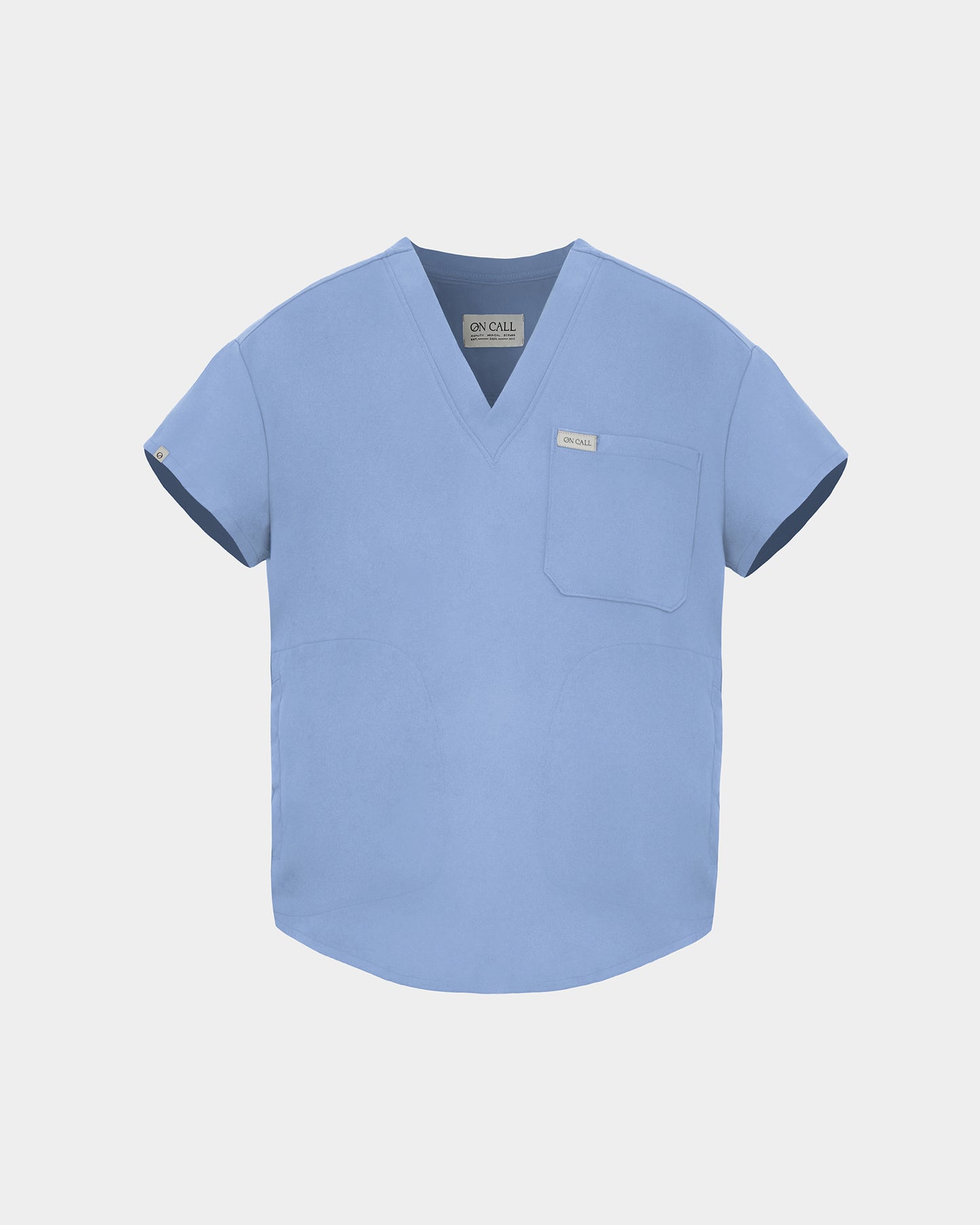A light blue scrub top with short sleeves, a V-neckline, and a chest pocket, shown against a light gray background.
