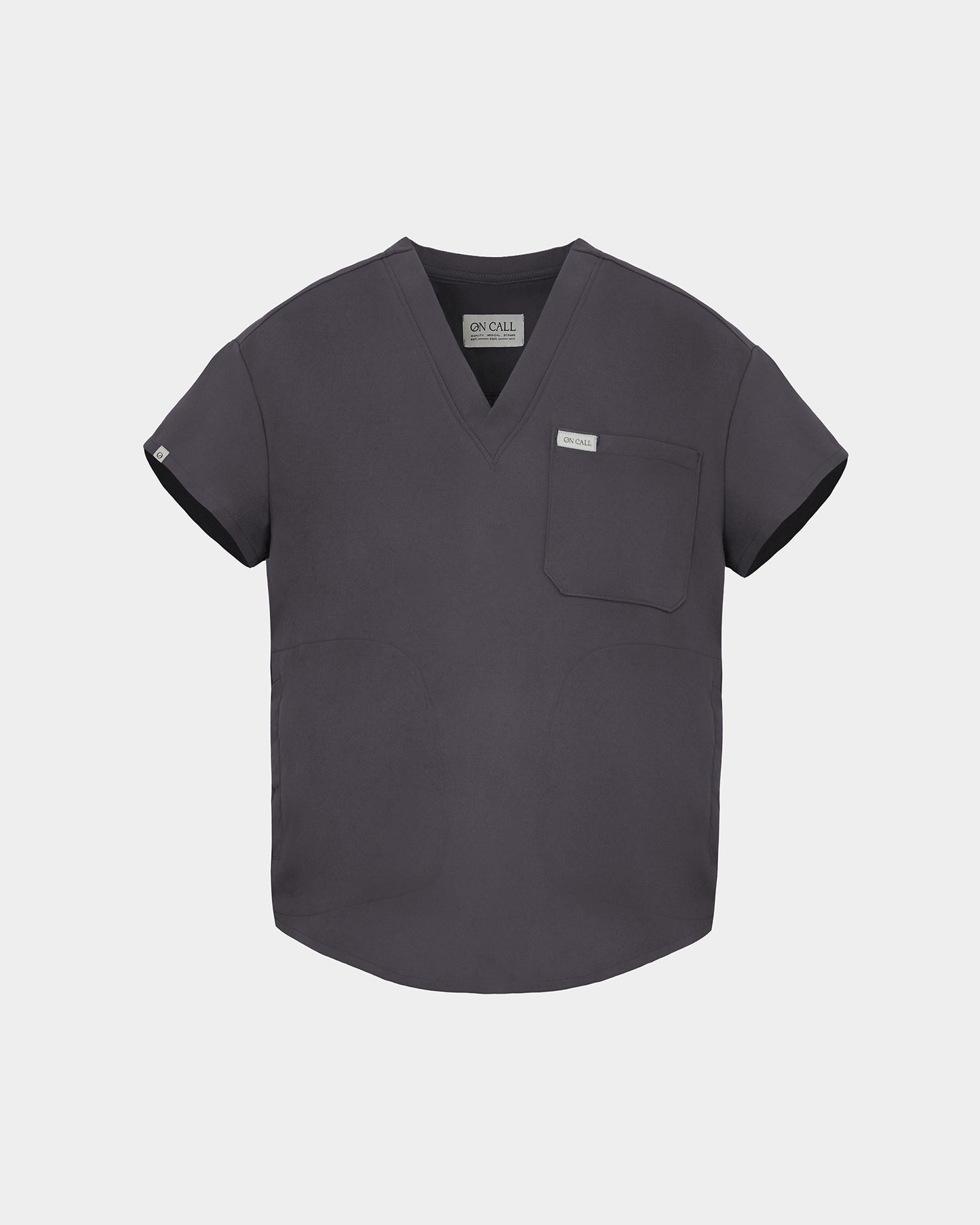 A dark gray V-neck scrub top with short sleeves, a chest pocket, and a small white brand tag on the left chest, displayed against a light gray background.