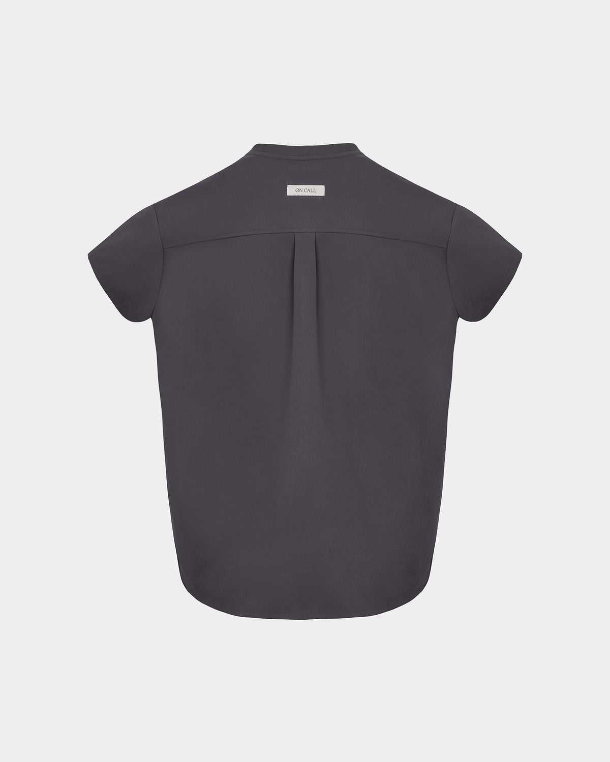 A dark grey short-sleeve scrub shirt shown from the back, featuring a subtle center back pleat and a small white brand label at the collar, set against a light gray background.