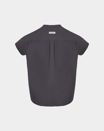 A dark grey short-sleeve scrub shirt shown from the back, featuring a subtle center back pleat and a small white brand label at the collar, set against a light gray background.
