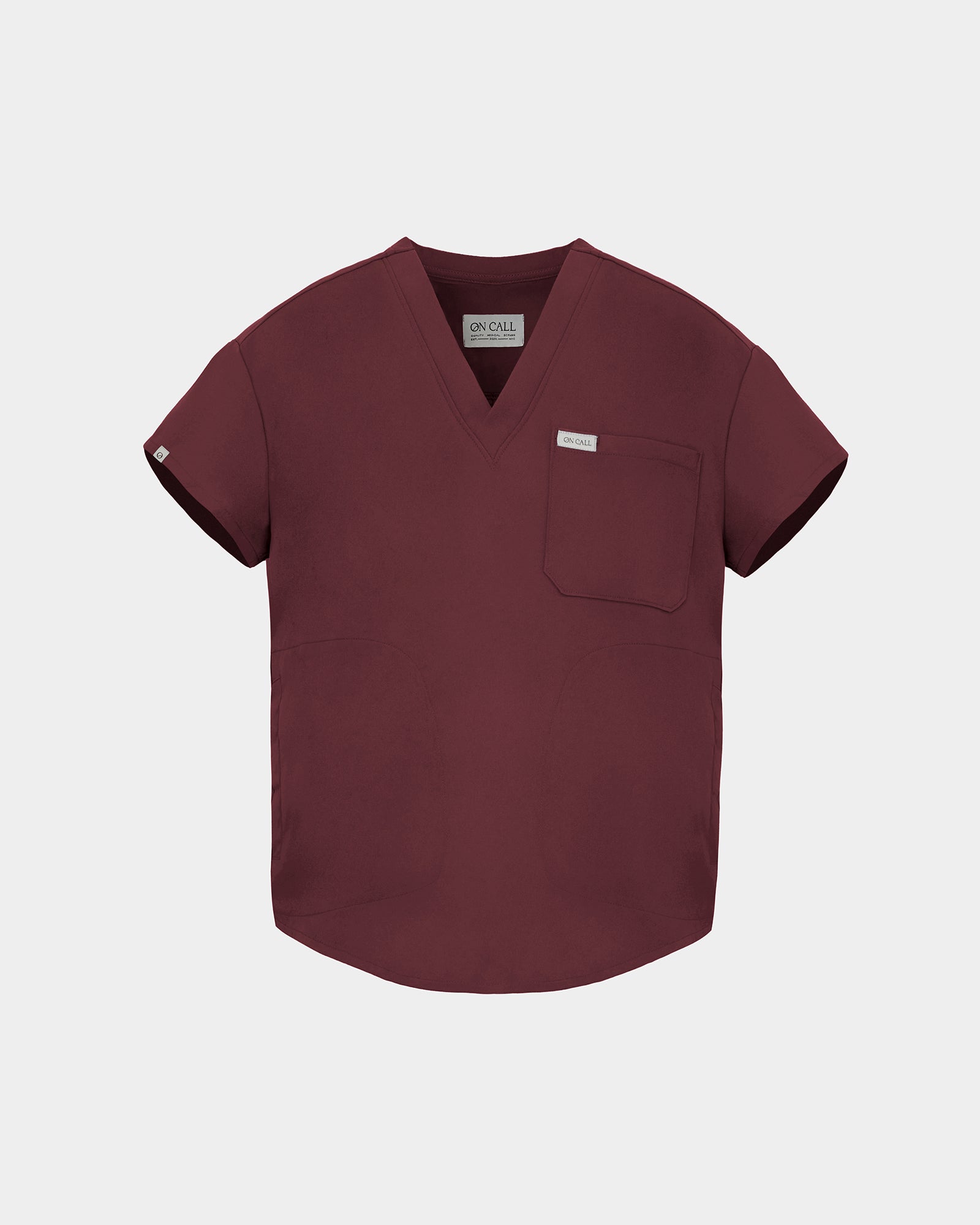 A short-sleeve V-neck scrub top in a deep heme red color, featuring a chest pocket with a small white label, displayed on a light gray background.