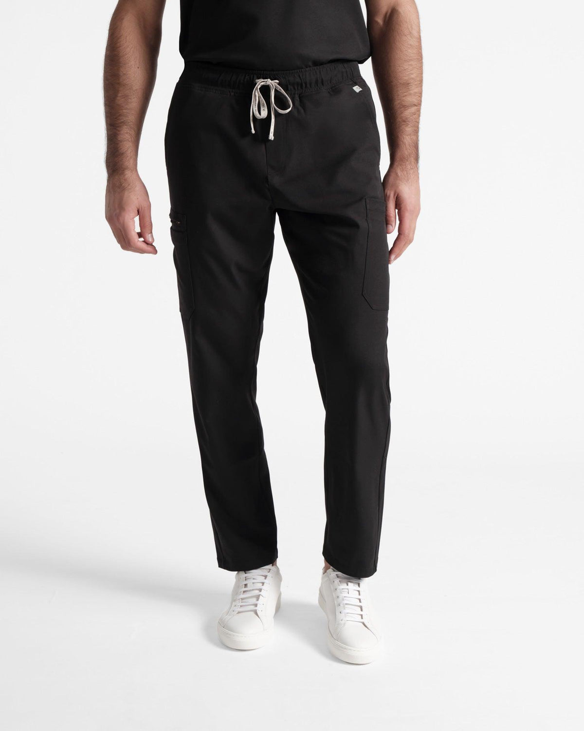 Waist down view of man wearing straight leg black cargo scrub pants.