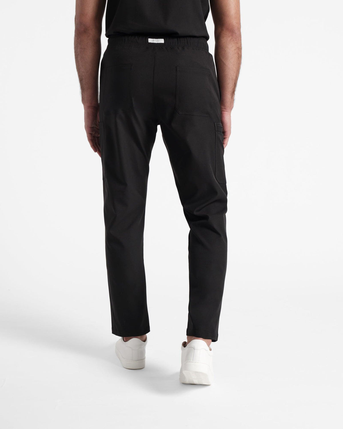 Back side view of man wearing straight leg cargo scrub pants with two back pockets and On Call branded fabric label at the waistband.