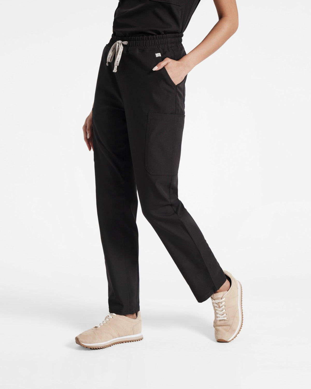 Angled view of woman in cargo straight leg scrub pant in black with hand in pocket.