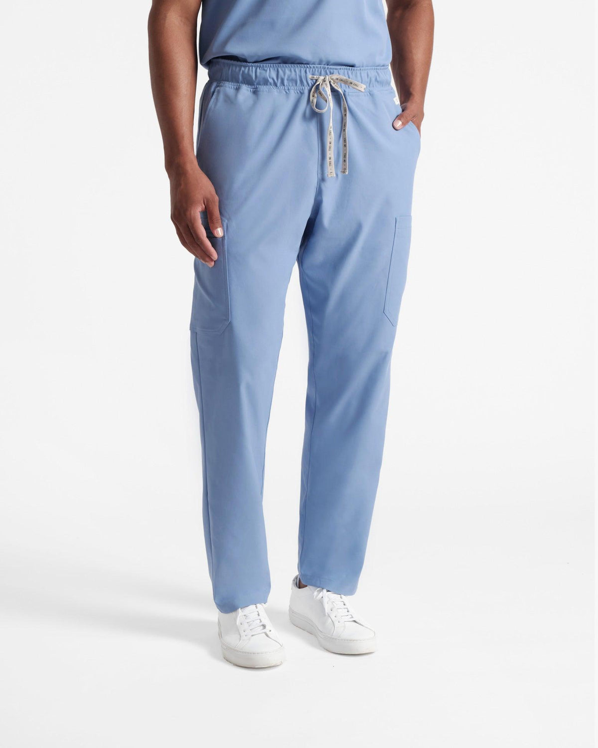 Man in light blue cargo scrub pants with hand in pocket.