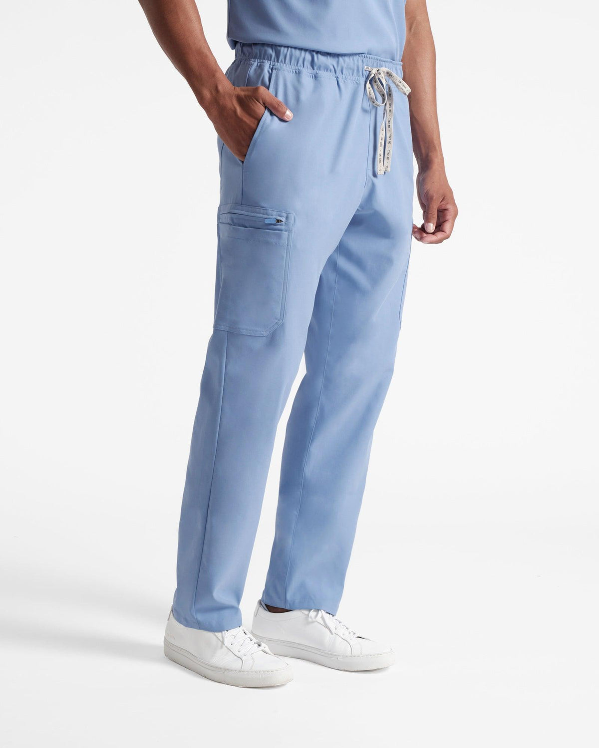 Angled side view of man in light blue cargo scrub pants with his hand in the waist pocket.