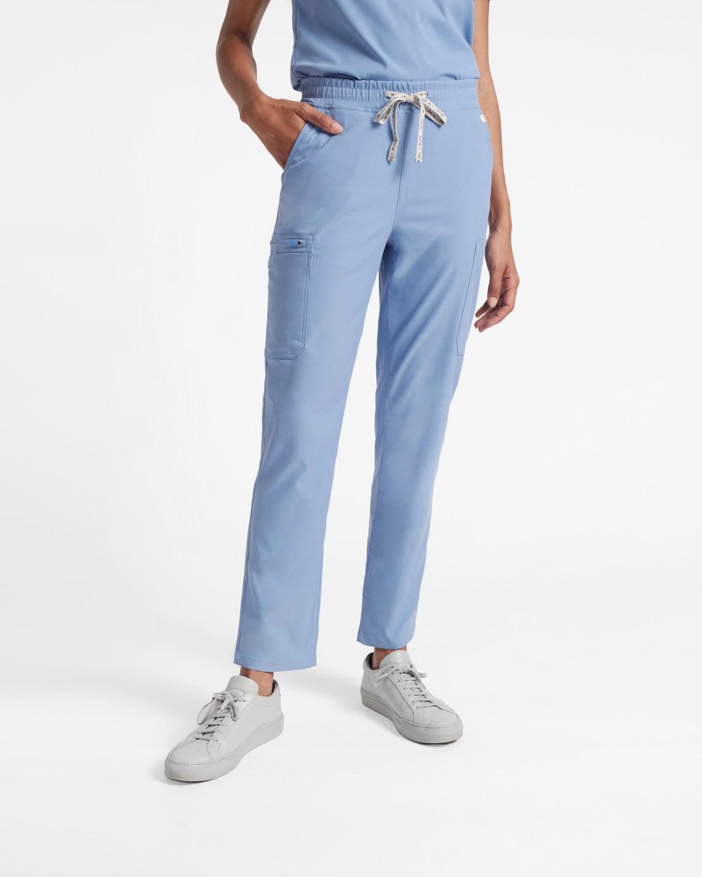 Woman wearing light blue cargo straight leg scrub pants with her hand in pocket.