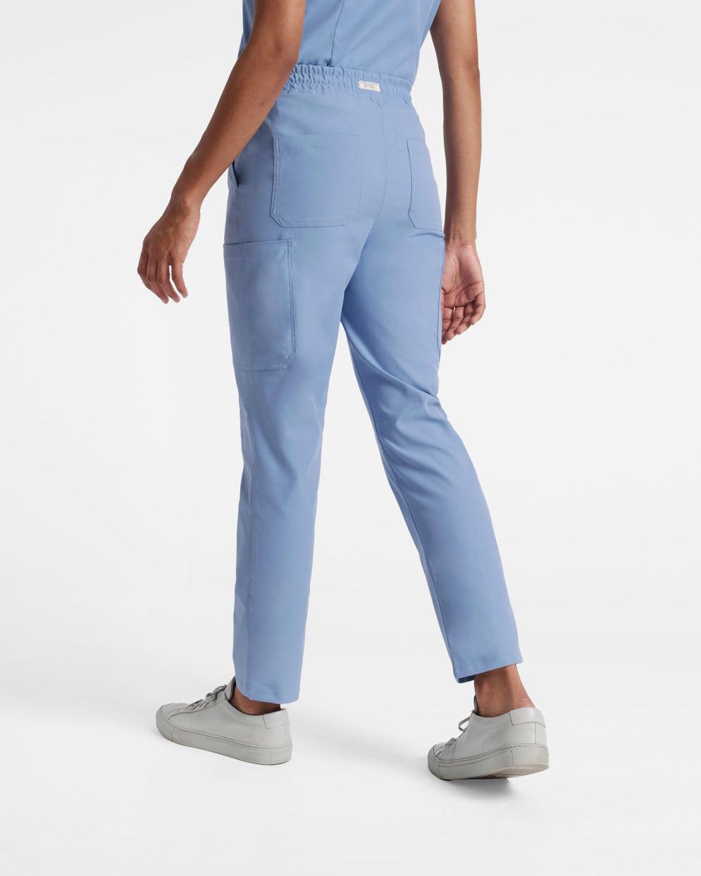 Back side view of woman wearing light blue cargo straight leg scrub pants with two back pockets. 