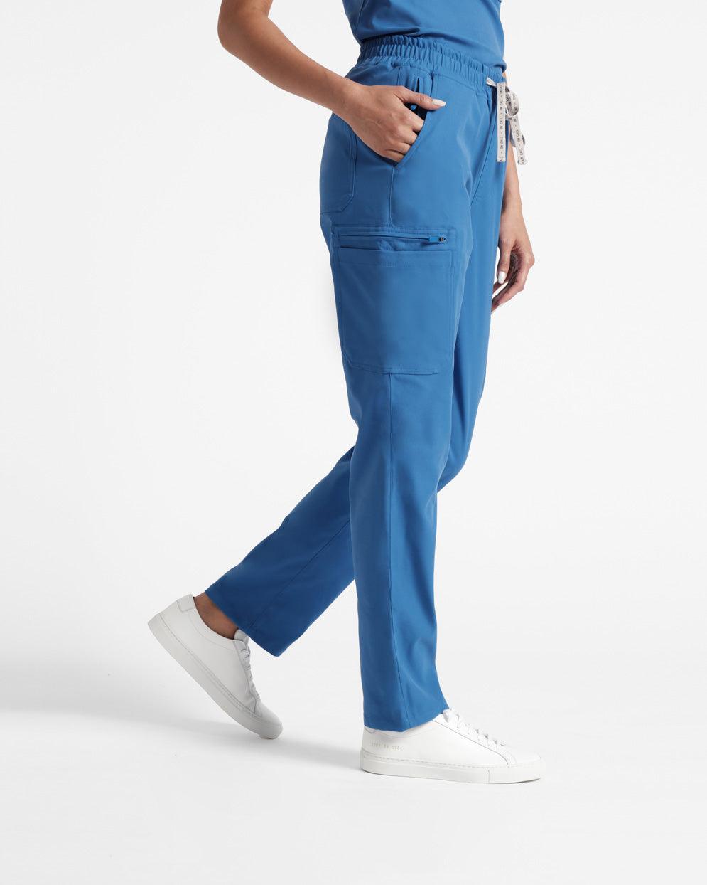 Side view of woman in bright blue straight leg cargo scrub pants with her hand in the pocket. 