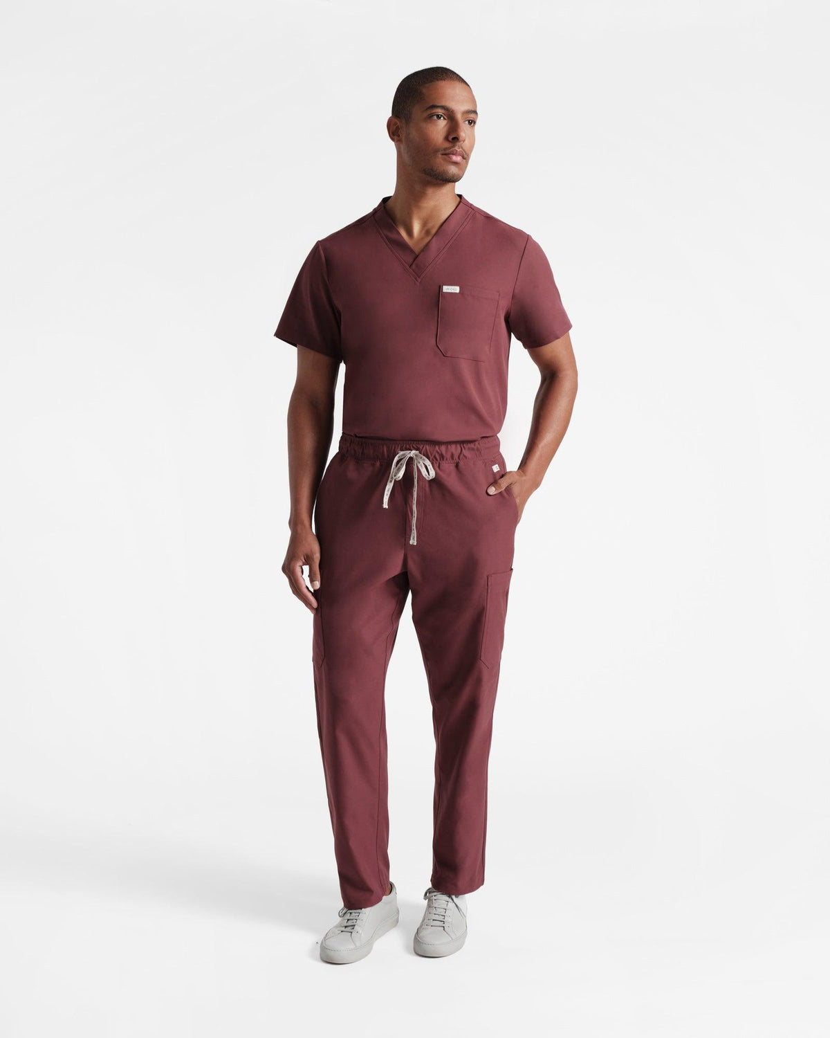 Man in deep red cargo scrub pants with a matching v-neck scrub shirt tucked in.
