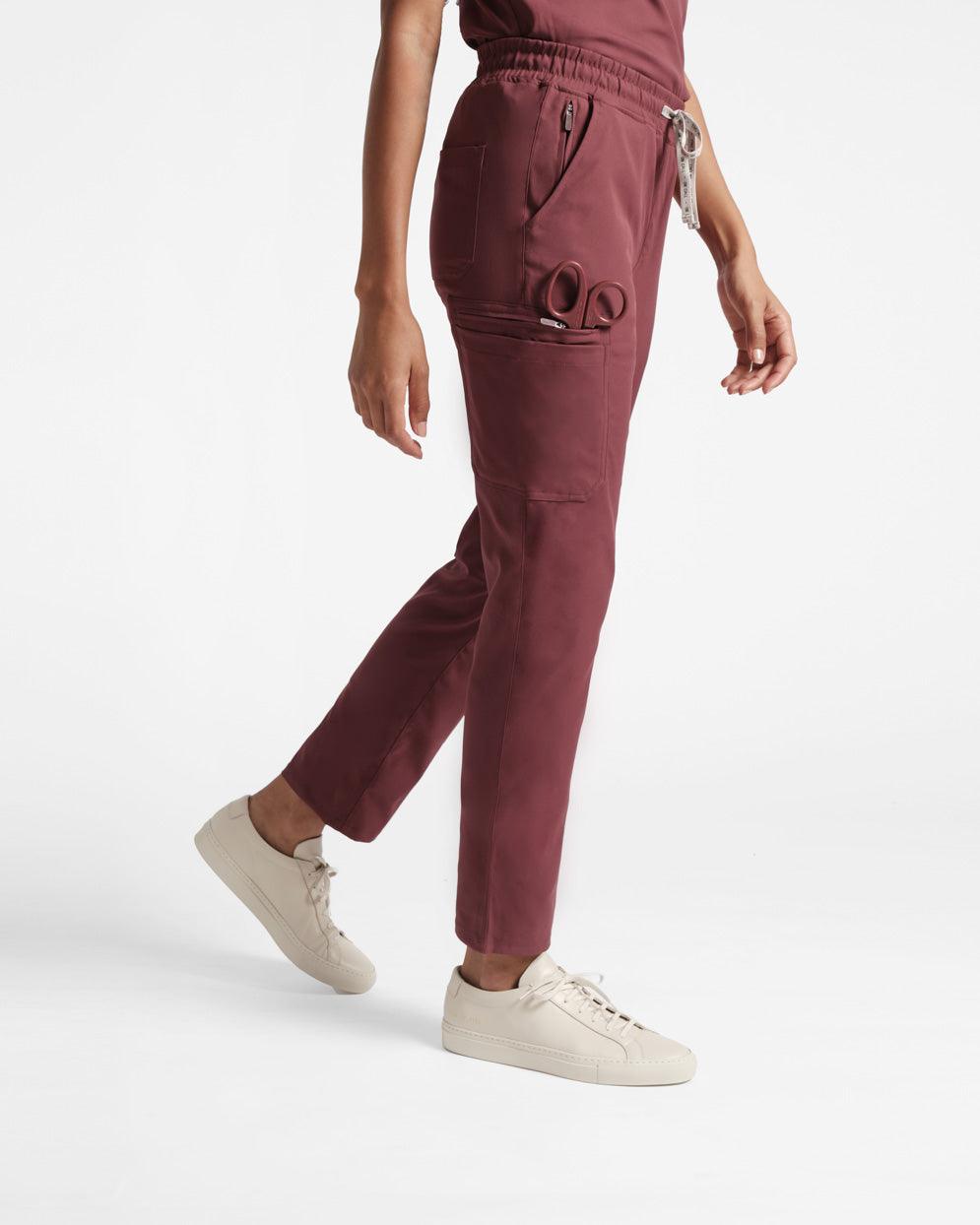 Side view of woman in deep red straight leg cargo pants with scissors in side leg pocket.