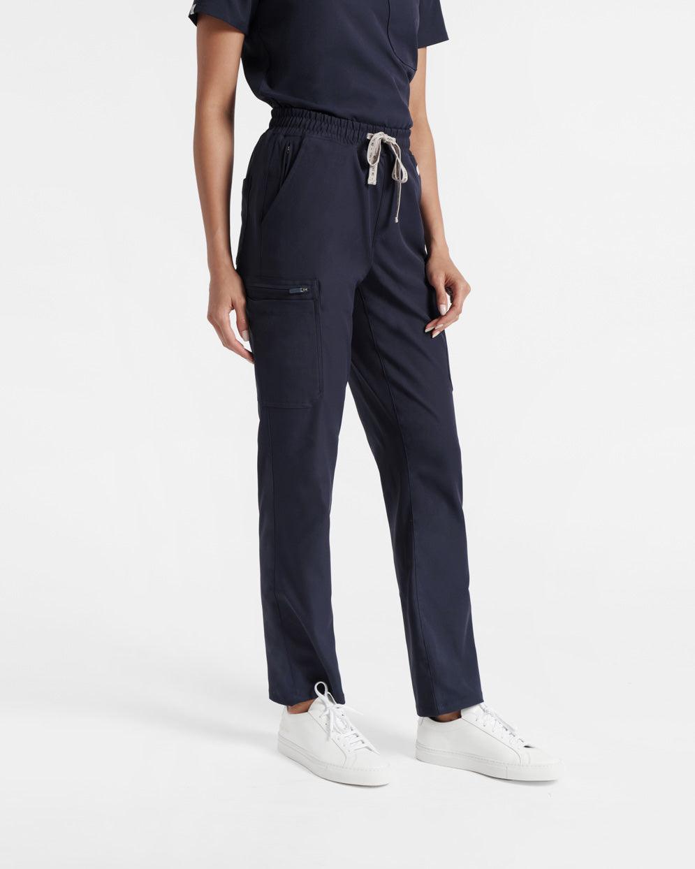 Angled front view of woman from the chest down in navy straight leg cargo scrub pants and matching shirt tucked in. 