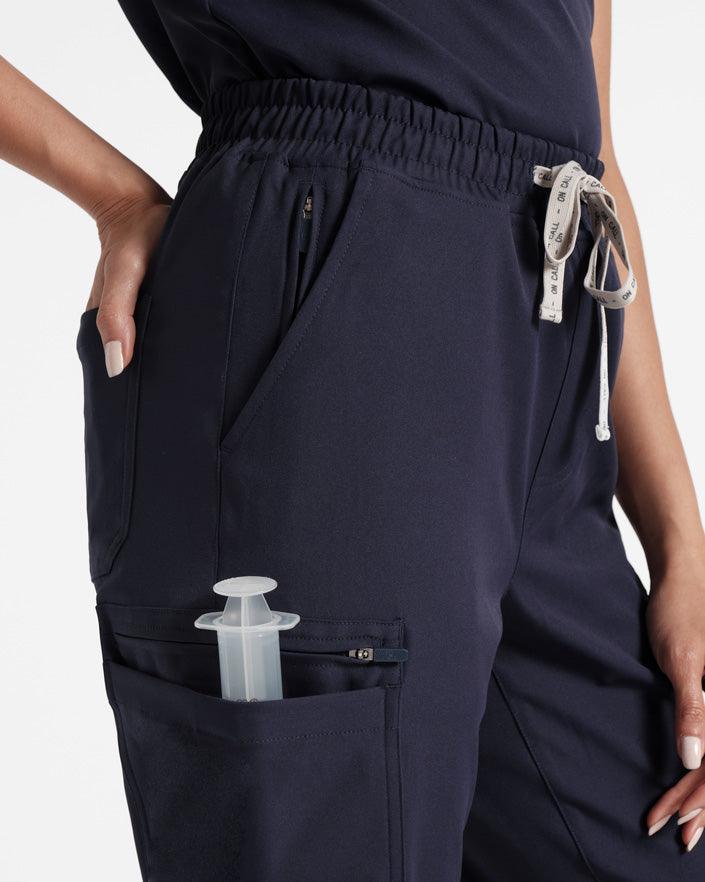 Detailed side view of woman in navy cargo straight leg pants with hand in back pocket. 