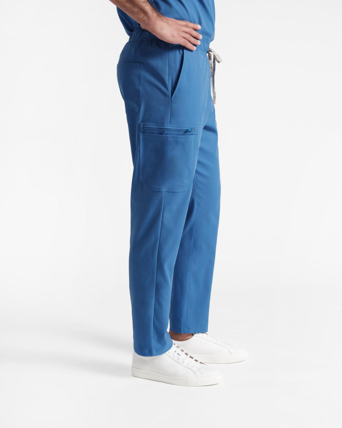 Side view of man in bright blue cargo scrub pants with a large side leg pocket.