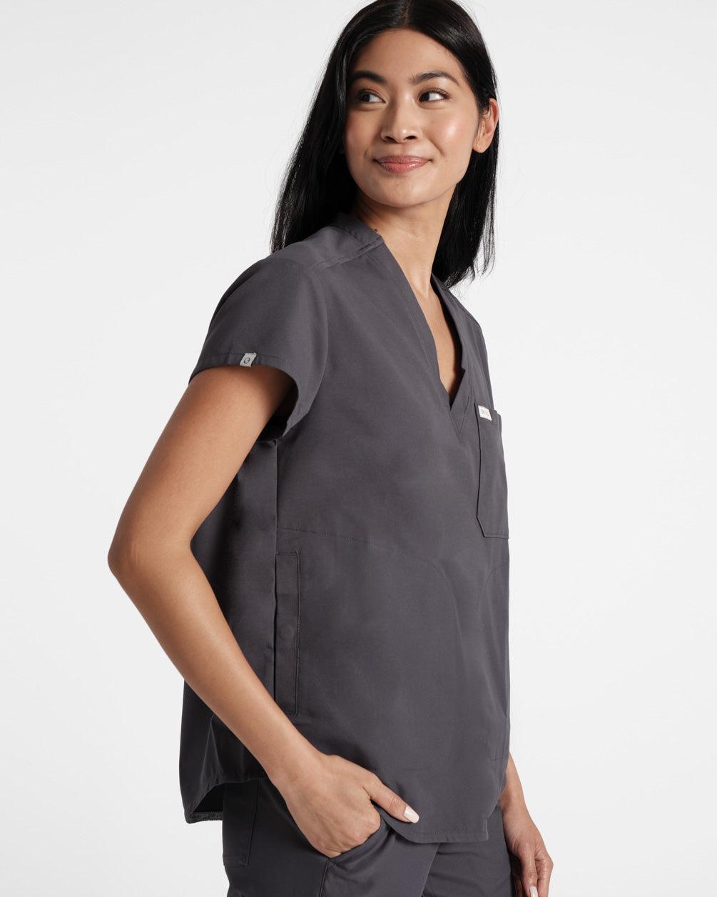 Side view of woman in dark grey scrub shirt with her hand in the matching pant pocket.