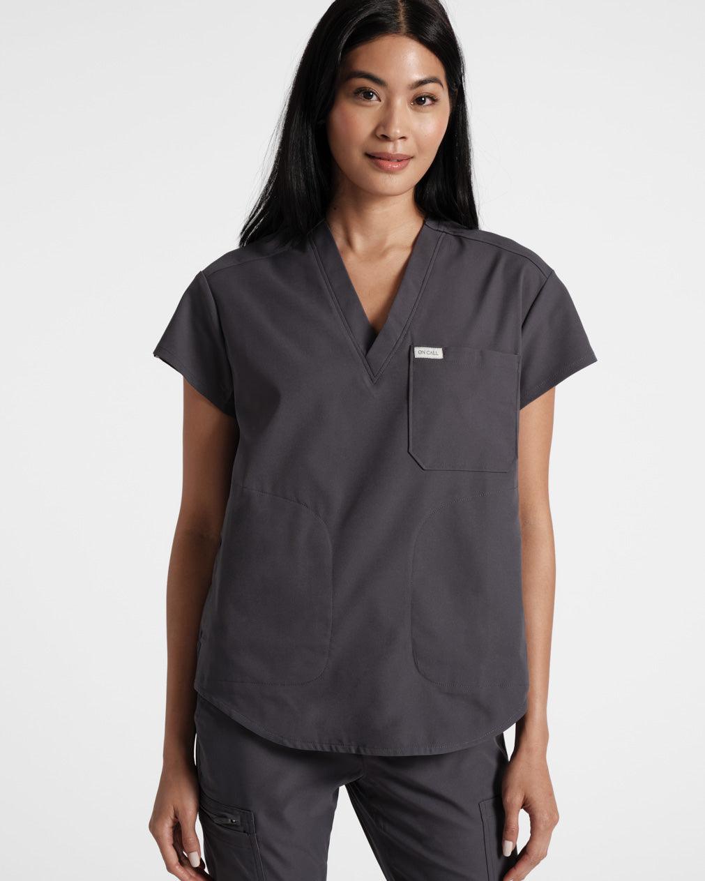 Woman in dark grey v-neck scrub shirt and matching scrub pants.