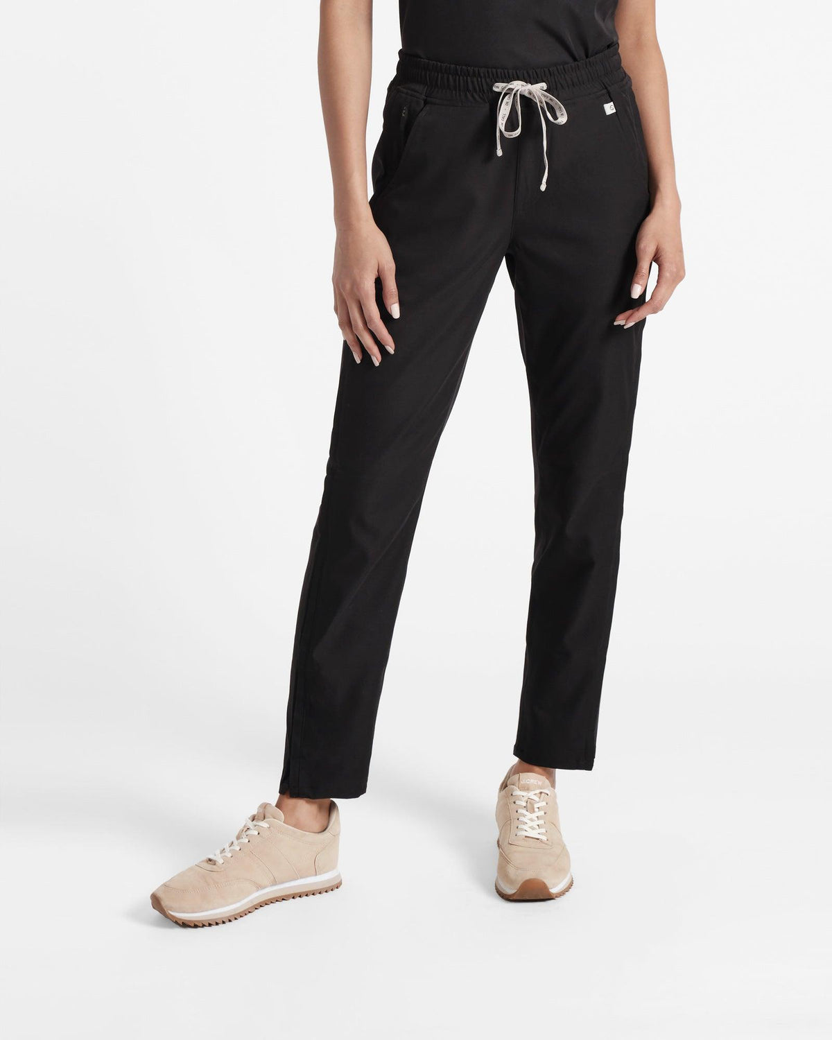 Woman wearing straight leg black scrubs with On Call branded waistband tie.