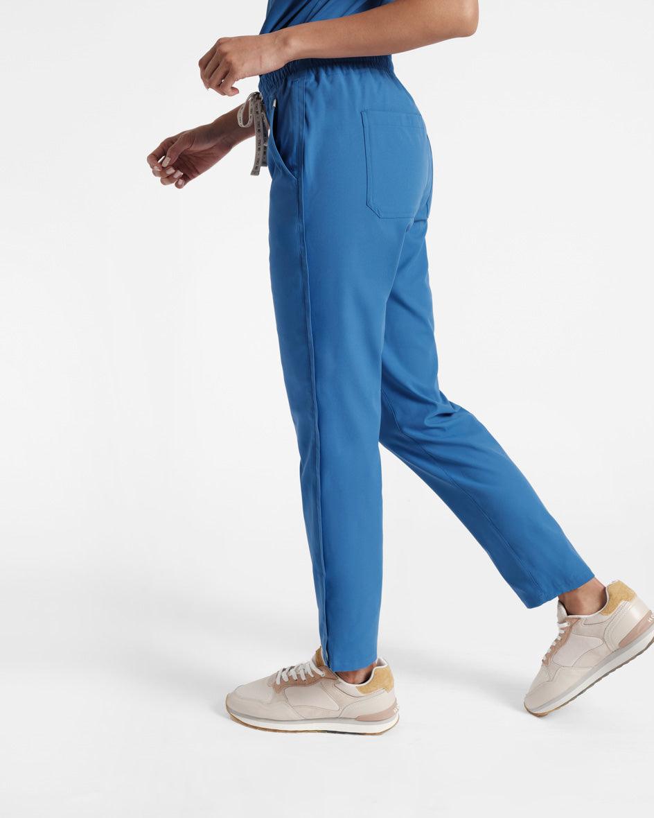 Side view of woman wearing bright blue scrub pants with back pockets.