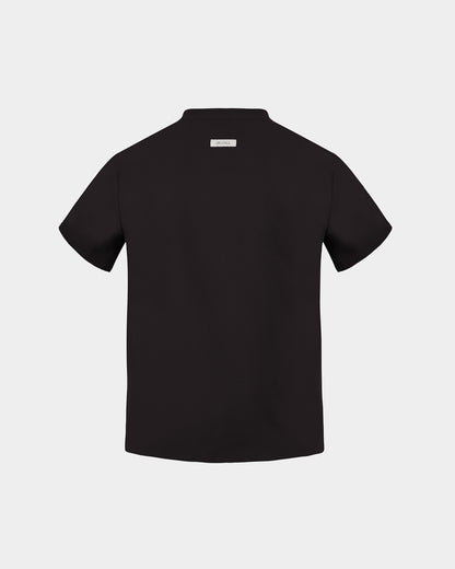 A black short-sleeve scrub shirt shown from the back, featuring a small rectangular brand label at the collar, set against a solid light gray background.