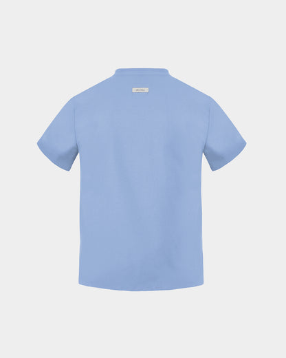 A light blue short-sleeve scrub shirt shown from the back, featuring a small rectangular brand label at the inner collar, set against a solid light gray background.