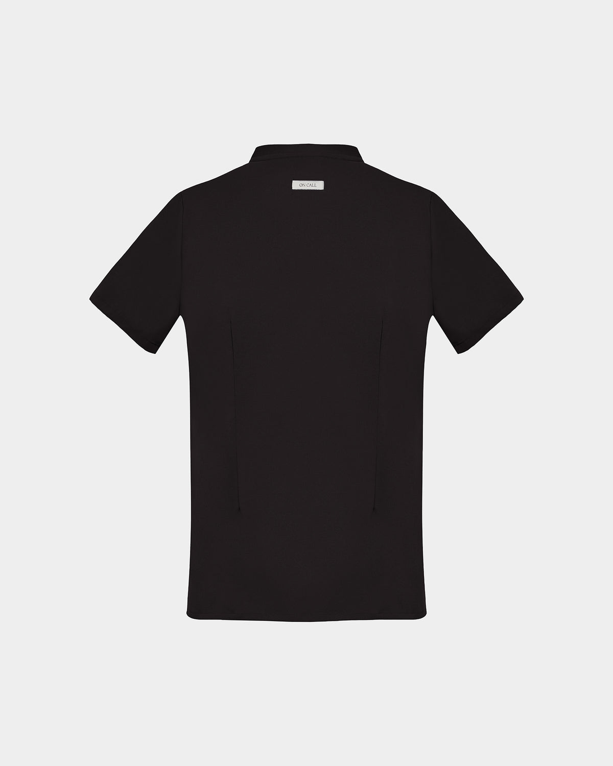 A back side view of a black short-sleeve scrub shirt with a logo label under the collar shown flat against a light gray background.