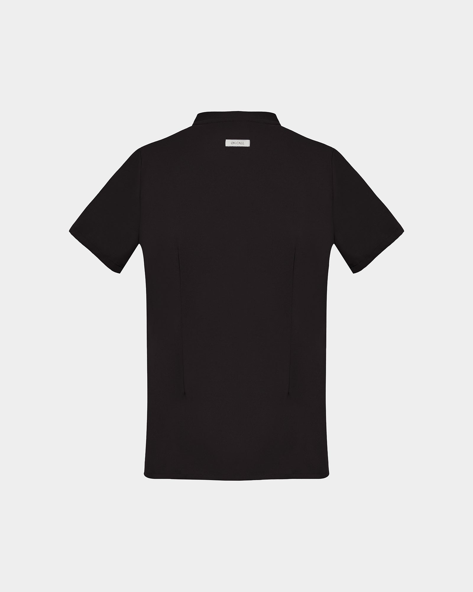 A back side view of a black short-sleeve scrub shirt with a logo label under the collar shown flat against a light gray background.