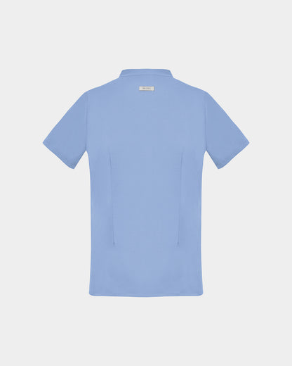 A light blue short-sleeve scrub shirt shown from the back, featuring two back darts, centered on a light gray background.