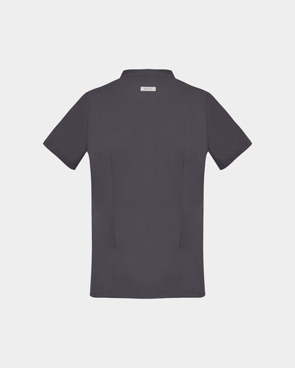 A dark grey short-sleeve scrub shirt shown from the back, featuring two back darts and a logo label, displayed on a light gray background.