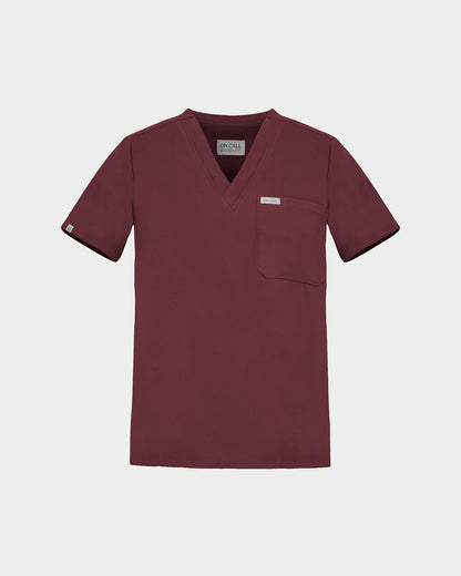 A short-sleeve V-neck scrub top in a deep heme red color with a chest pocket and a small white brand label, shown on a light gray background.