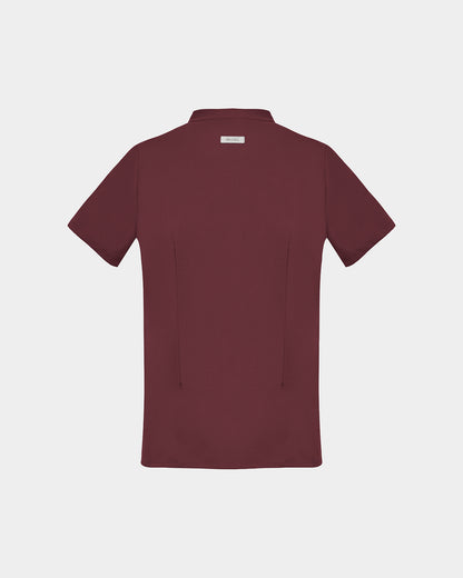 A short-sleeve scrub shirt in a deep heme red color, shown from the back, featuring two back darts, against a light gray background